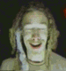 A person with light brown hair and a light-colored shirt appears in a of showing sequential facial expressions and mouth positions against a dark background