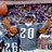 A pixelated image of a football player in a gray jersey with number 20, arms raised in celebration, surrounded by blurred crowd and other players.