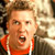 Pixelated static image of a person with light brown hair wearing an orange shirt, mouth open in mid-expression against a blurred background.