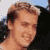 Static pixelated image of a person's face with brown hair and light skin tone, cropped closely to show upper head and shoulders against a blurred background.