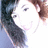 A pixelated image of a person with dark hair and light skin, smiling, with a bright background.