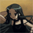 Pixelated anime-style character with long dark hair, wearing a black top with white shoulder accents, against a gradient background transitioning from brown to yellow.