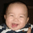 Pixelated close-up of a smiling baby with closed eyes wearing dark blue and white striped clothing against a black background.