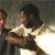 Two figures in a dynamic pose, one figure appears to be holding or interacting with the other against a muted background.