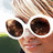 A pixelated image of a person wearing white sunglasses with brown lenses, partially visible face and hair.
