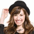 A woman with long brown hair and a black beret appears in three sequential poses against changing backgrounds.