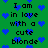 Green background with blue pixelated hearts and repeated black text reading "I am in love with a cute blonde" arranged vertically.