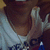 Pixelated image of a person with brown hair wearing a white shirt, making a hand gesture near their face.