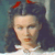 Pixelated portrait of a person with dark hair styled in a high bun, wearing a white collar and red hair accessory against a muted blue background.