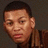 Pixelated close-up of a person with short dark hair, light skin tone, and neutral expression against dark background.