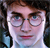 Pixelated close-up of a person with brown hair, round eyeglasses, and a light-colored shirt against a dark background.