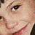 A pixelated image of a person with dark hair smiling, showing three distinct facial angles in a