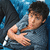 Pixelated image of a person with dark hair wearing a light blue shirt, extending an arm forward against a blue and black background.