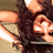Pixelated close-up of a person with dark hair holding an object near their face, set against a light background.