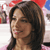 A pixelated close-up of a person with dark brown hair, light skin, and a slight smile, set against a blurred background with red and blue elements.