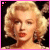 Pixelated image of a woman with blonde curly hair, red lips, and light skin against black background; pink border frames the image.