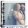 A static image shows a couple embracing near blue lockers, the woman in a white dress with short sleeves and the man in a dark shirt.