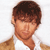 Pixelated image of a person with short brown hair wearing a white shirt and brown jacket against a white background.