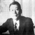 Black-and-white photograph of a person in formal attire beside bold text reading 'NHD' with red horizontal bars and partially obscured words below.
