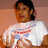 Pixelated image of a person with dark hair wearing a white shirt featuring red and blue horizontal stripes against a brown background.