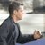 Pixelated image of a person in profile view wearing dark clothing with a light background and blue lower section.