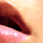 A close-up of lips with glossy pink lower lip and dark brown upper lip against a light skin tone background, next to green text reading "Original Icons .com" on dark green.