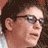 Static 48x48 pixel icon showing a close-up of a person's face with dark hair and sunglasses, rendered in low-resolution pixel art style with brown and beige tones.