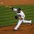 A baseball pitcher in mid-pitch on a field with green grass and brown dirt, captured across four showing motion progression