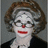 Pixelated image of a person with white face paint, red lips, and a red nose on the left; black background with pixelated text on top right and bottom left.