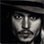 Pixelated grayscale portrait of a person with dark hair and a dark head covering, set against a solid black background.