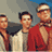 Pixelated static image of three men in a group pose with varied clothing and neutral expressions against a gradient background.