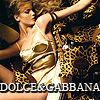 A woman in a gold and leopard-print outfit poses with arms raised against a dark background, with 'DOLCE & GABBANA' text at the bottom.