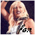 A pixelated image of a person with long blonde hair wearing a white sleeveless top, smiling broadly with arms raised against a dark background.