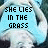A static image of a person lying on grass with text overlays in three , the top reading "SHE LIES IN THE GRASS," "STARING UP AT THE SKY," and "WONDERING IF HE IS THINKING" from left to right