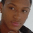 A pixelated close-up of a person's face with brown skin tone, dark eyes, and short dark hair against light background.