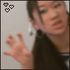 A person with long dark hair and earrings extends their right hand forward, while three small heart icons in the top-left corner change color from black to orange.
