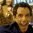 A 4-frame animated contact sheet showing a man in a dark blue shirt with varying facial expressions against a blurred background of another person and buildings.