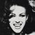 Pixelated grayscale image of a smiling face with closed eyes, dark hair, and a black background.