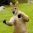 Pixelated image of a light brown animal with dark eyes and nose, standing on green grassy background.