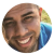Pixelated circular image of a smiling person with brown hair and blue eyes, featuring a rainbow-colored gradient on the right side.