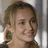 Static pixelated image of a person with light brown hair styled in two braids, wearing dark clothing against a blurred background.