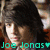 Pixelated image of a person with dark hair and light skin, wearing a red garment, with teal text reading 'Joe Jonas' and a heart symbol at the bottom.
