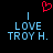 Red pixelated heart above two identical blue text blocks reading 'I LOVE TROY H.' on black background.