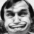 Black-and-white pixelated image of a person with long dark hair, closed eyes, and a broad smile showing teeth.