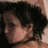 Pixelated close-up of a person with dark hair and light skin, showing partial facial features against a dark background.