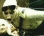 Animated sequence showing a person in military-style gear leaning forward, then transitioning to seated poses with hands clasped and long hair visible.