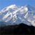 A pixelated landscape with dark ground, light clouds, and blue sky, showing no distinct subjects or text.