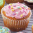Pixelated image of a cupcake with pink frosting and multicolored sprinkles on a brown wrapper.