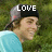 Pixelated image of a person wearing a black cap with white text and light blue shirt against green background.