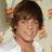 Pixelated portrait of a person with short brown hair wearing a white shirt, smiling against a light background with orange and gray decorative elements.